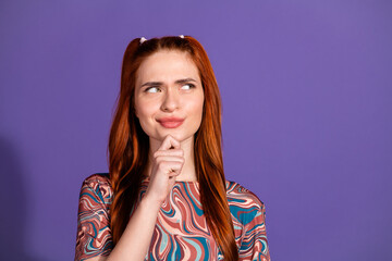 Fototapeta premium Young red-haired woman making a thoughtful gesture against a purple background, ideal for lifestyle or advertising themes