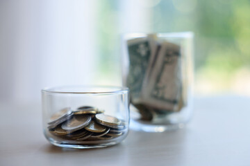 Glass jars with money on light table indoors, selective focus