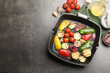 Pan with grilled vegetables and spices on grey table, flat lay. Space for text