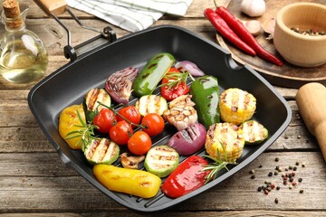 Pan with grilled vegetables and spices on wooden table, closeup