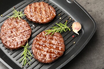 Pan with grilled patties and spices on grey table, above view