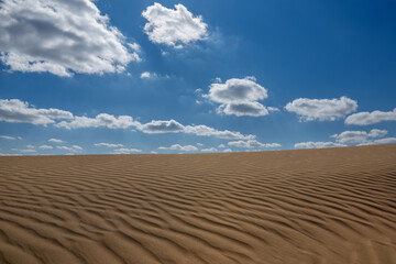 Clouds in the blue sky above a sand dune