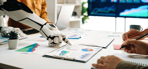 A robot collaborates with a human in a modern office showcasing various charts and graphs on a...