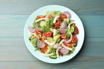 Delicious salad with squid, vegetables and walnuts on light blue wooden table, top view