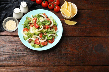 Delicious salad with squid, vegetables and walnuts served on wooden table, flat lay. Space for text