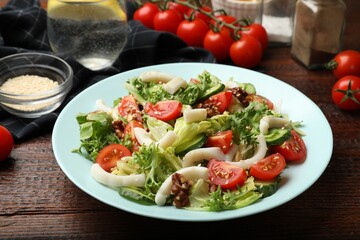 Delicious salad with squid, vegetables and walnuts on wooden table, closeup