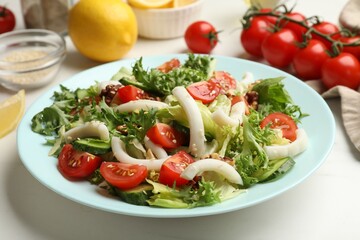 Delicious salad with squid and vegetables on white table, closeup
