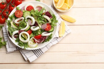 Delicious salad with squid rings and vegetables served on light wooden table, flat lay. Space for text