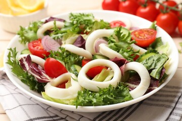 Delicious salad with squid rings and vegetables on table, closeup