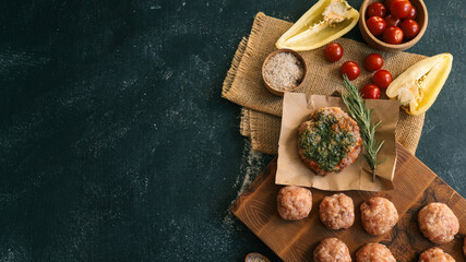 Delicious burger with fresh ingredients and meatballs on a wooden board.