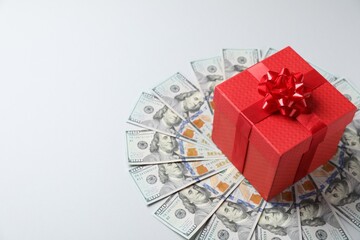 Gift box on dollar banknotes against light grey background. Space for text