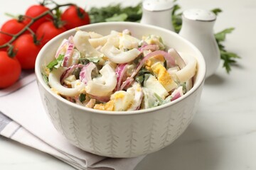 Tasty salad with squid rings, onion and eggs served on white marble table, closeup
