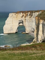 Cliffs of Étretat in Normandy, France during daytime, with natural rock arch and sea view framed...