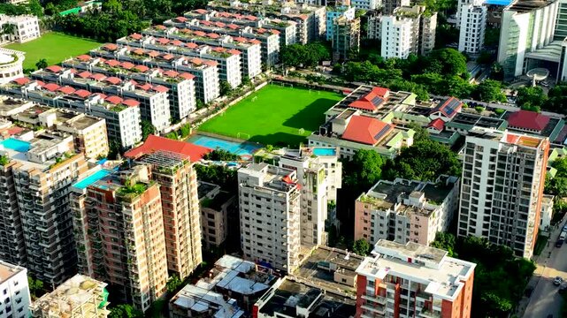 High angle view of a dense residential area with apartment buildings, green spaces, and a sports field dhaka, bangladesh