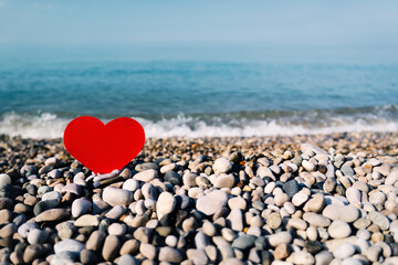Red paper heart on the seashore. Beach, sea, vacation, joy. Love for the sea