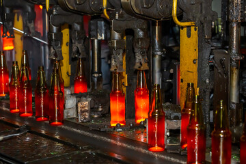 Glass factory, production of glass containers. Molten glass is blown into molds. Robotics in industry. Modern technologies, robotic machines produce products. Technological work at the plant.