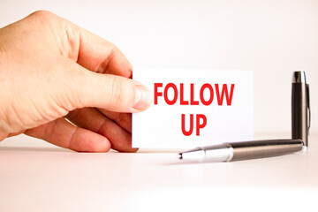 Follow up symbol. Concept word Follow up on beautiful white card. Beautiful black pen. Beautiful white paper background. Businessman's hand. Business follow up concept. Copy space.