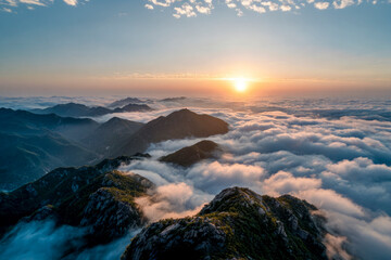 Fototapeta premium Sun rising over mountain peaks overlooking a sea of clouds