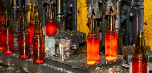 Glass factory, production of glass containers. Molten glass is blown into molds. Robotics in industry. Modern technologies, robotic machines produce products. Technological work at the plant.
