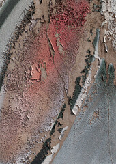 Close-up of old peeling paint on a wall surface. Weathered, cracked and flaking layers create a textured and distressed background.