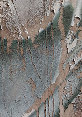 Close-up of old peeling paint on a wall surface. Weathered, cracked and flaking layers create a textured and distressed background.
