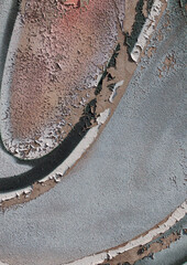Close-up of old peeling paint on a wall surface. Weathered, cracked and flaking layers create a textured and distressed background.