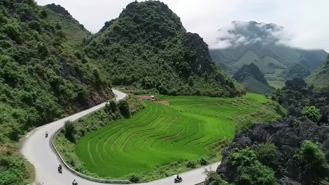 Winding road through majestic mountains with green fields and clouds