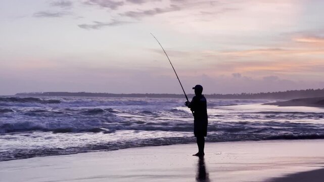 Close-up Silhouette of Fisherman Surf Fishing at Sunset or Sunrise