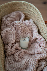 Pink knitted blanket in a basket bag. Cozy home decor.