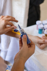 hand takes Glitter in plastic bottles. Decorative sequins to give shine, create festive atmosphere. make-up tools for face painting master. painting with glitter. various bottles. High quality photo