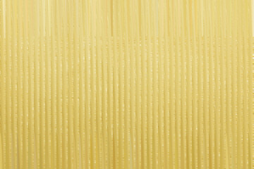 Close up of uncooked spaghetti pasta forming a textured yellow background perfect for culinary themes and food related visuals