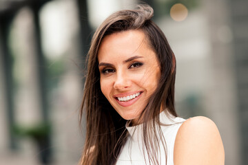 Obraz premium Beautiful woman smiling in an urban outdoor setting, symbolizing confidence, elegance, and modern lifestyle on a sunny day