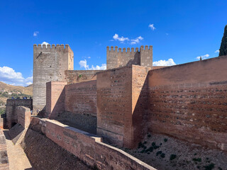 M&auml;chtige Festungsmauern der Alhambra in Granada, Andalusien, Spanien. Historische Architektur mit T&uuml;rmen und blauen Himmel im Hintergrund, UNESCO-Weltkulturerbe.
