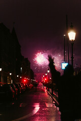 Fireworks Exploding Over a City Street with Silhouette of a Person and Red Lanterns
