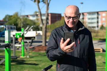 Senior man in sportswear using mobile phone while exercising in the park