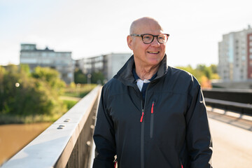 Portrait of a smiling senior man standing on a bridge in the city