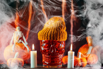 Halloween bloody cocktail in a skull glass with candlelight and smoky background