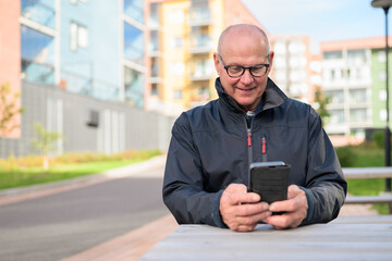 Portrait of a senior man using his mobile phone in the city while sitting