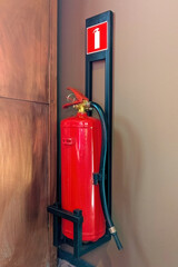 Red fire extinguisher mounted on the wall with a safety sign above it. Essential fire safety equipment in an indoor environment.