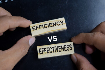 Efficiency vs effectiveness on stacked wooden cubes on the table. Business and finance concept