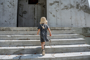 Child girl climbs the steps into the stone building