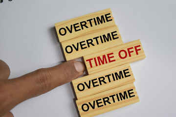 Overtime or Time off on stacked wooden cubes on the table. Business and finance concept