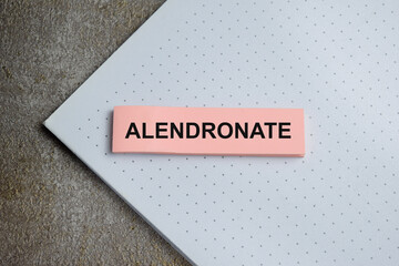 Concept of alendronate write on sticky notes isolated on Wooden Table.