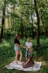 Fototapeta premium A young mother joyfully plays with her daughter and son in nature, sharing authentic family moments of laughter and connection. Pure love and outdoor happiness