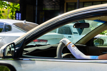 Woman driving car with white gloves and sun protection sleeves