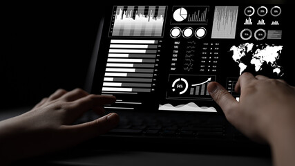 Close-up of hands interacting with a laptop featuring data analytics and statistics displayed in graphs and charts, showcasing a dark workspace environment. Impute