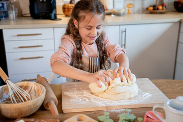 Little cute girl baking cookies in the kitchen. Homemade pastries. Cozy autumn.