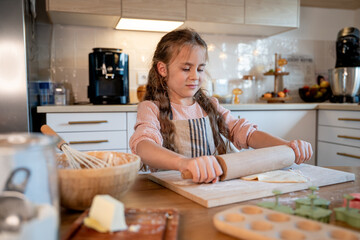 Little cute girl baking cookies in the kitchen. Homemade pastries. Cozy autumn.