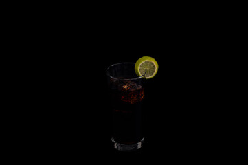 Dark beverage with lime slice on black background
