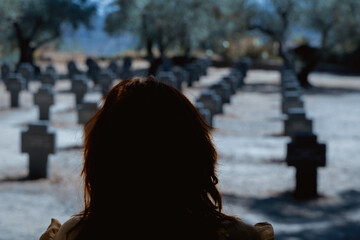 Silhouetted figure looking at gravestones, depicting remembrance and loss in a solemn setting